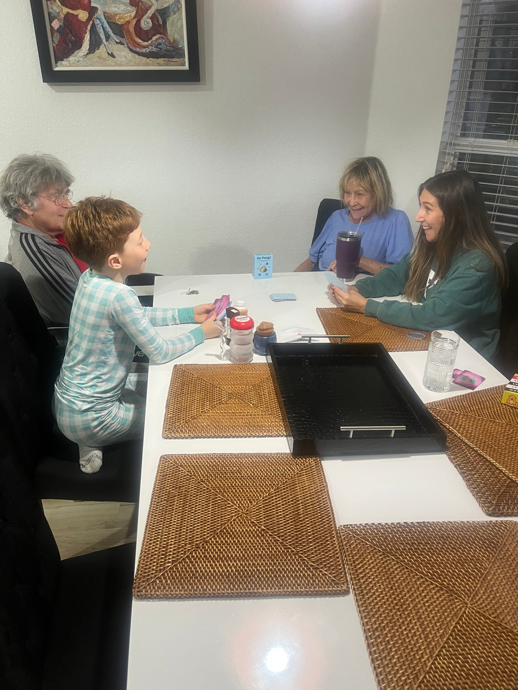 family of four playing go poop!, including a mom, kid and grandparents